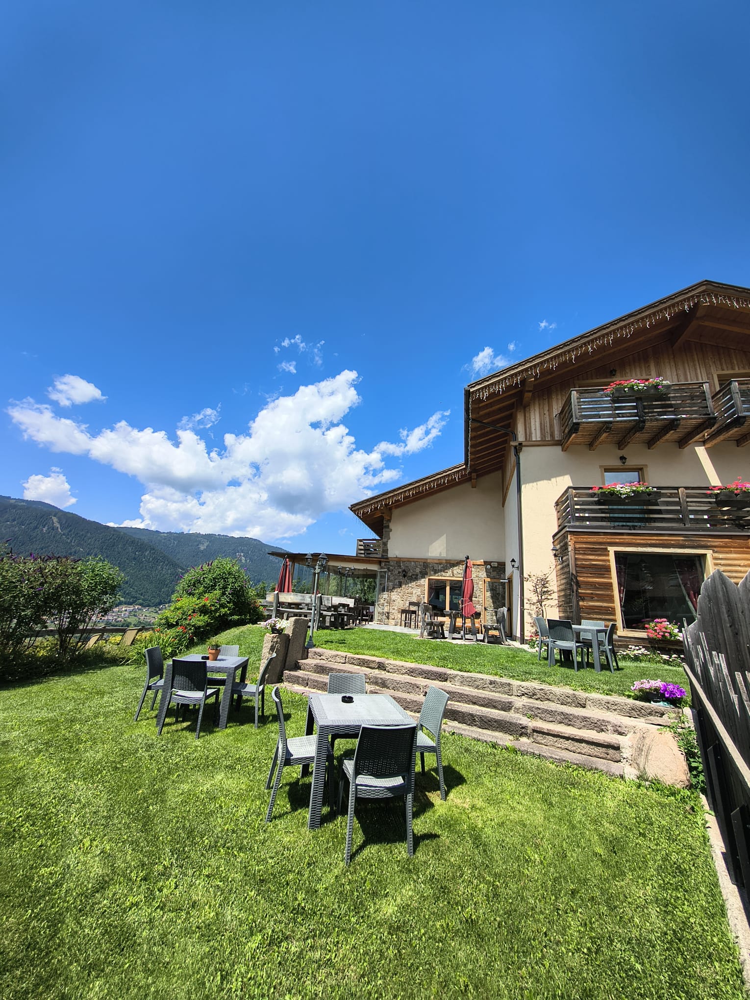 Esterno dello chalet con giardino panoramico e tavoli all'aperto