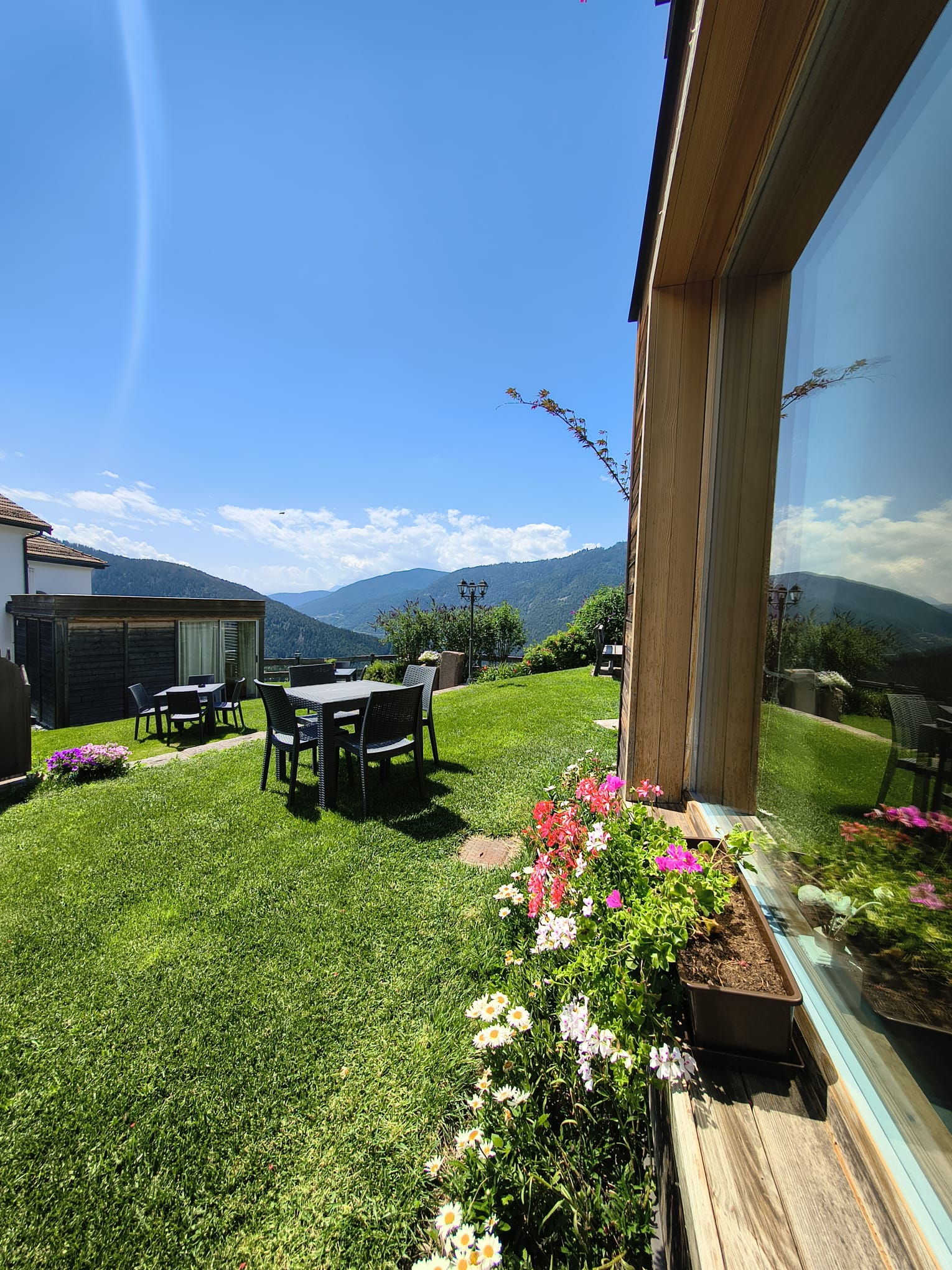 Giardino fiorito dello chalet con tavoli e vista sulle montagne